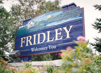 Blue, green City of Fridley Welcome Sign in between the trees